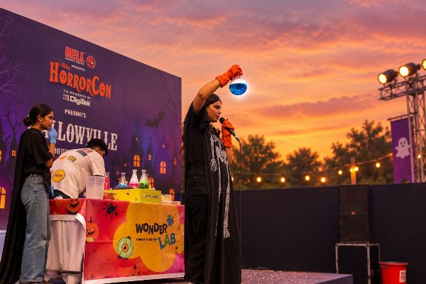 A performer holding up a glowing blue potion on the Wonder Lab stage at sunset