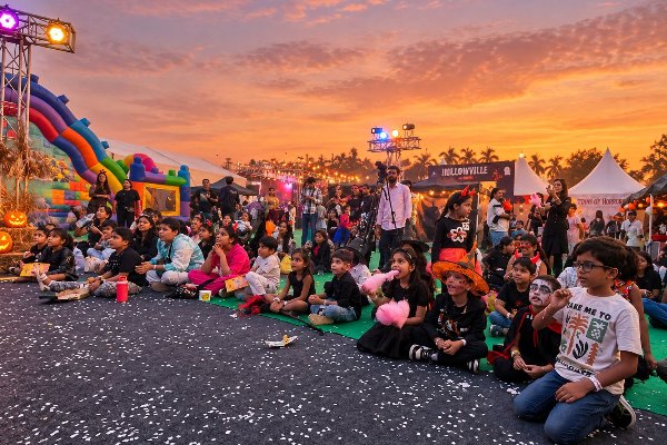 Kids in costumes enjoying the show at sunset with a bouncy castle behind